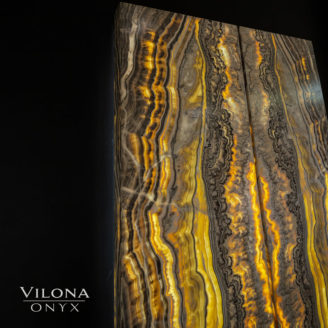 Onyx wall panel with tall vertical amber, gold, and gray ribbon-like onyx patterns.
