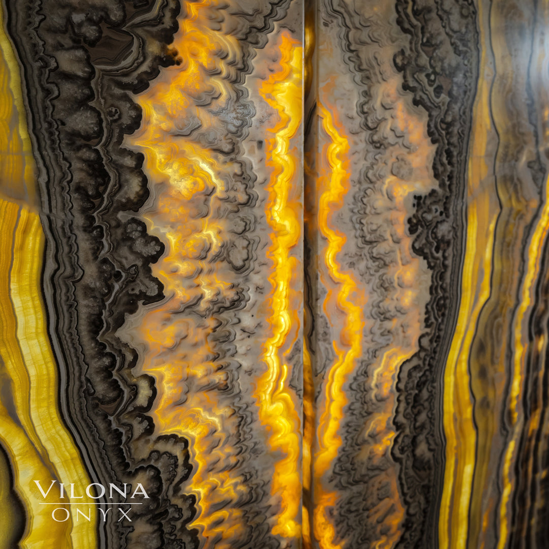 Close-up onyx wall panel surface with golden glow lines and dark curving striations.