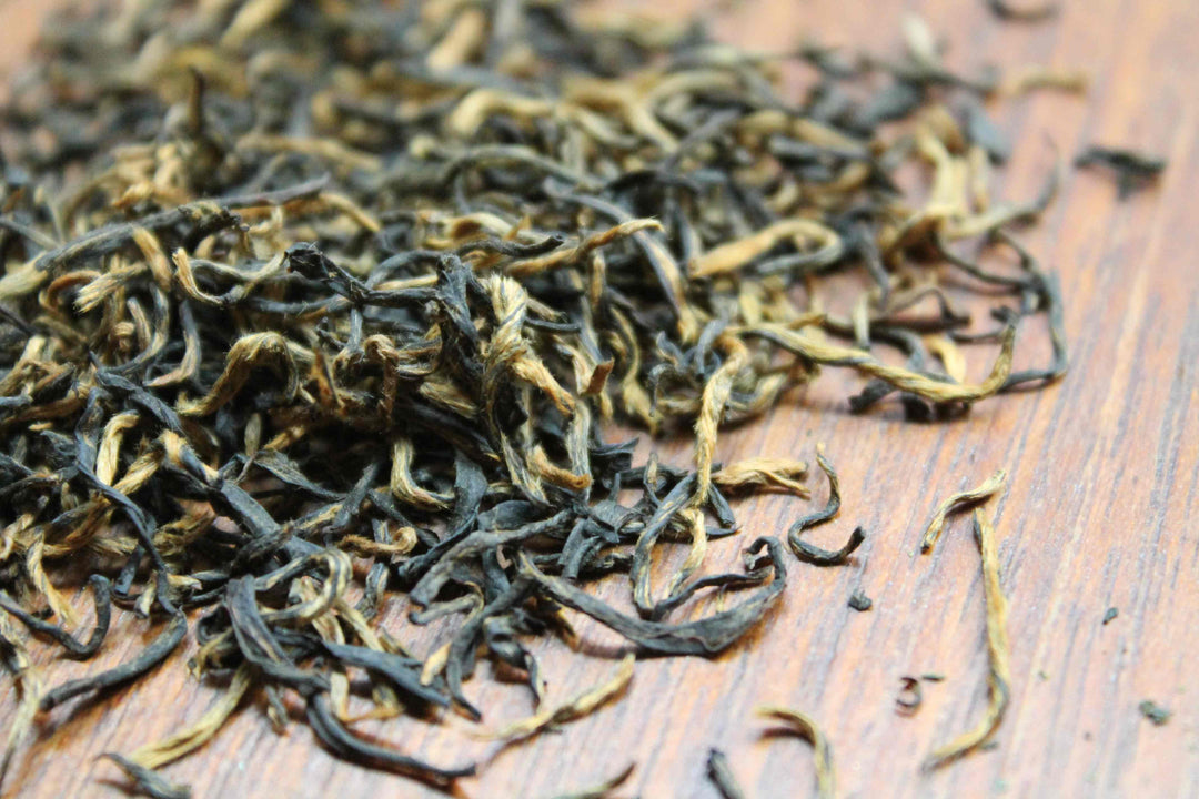 Loose leaf tea leaves, dark green and golden strands