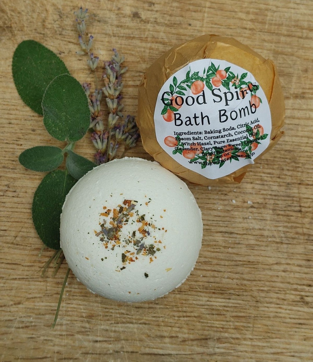 White bath bomb with speckled bits, labeled "Good Spirits" in brown wrap