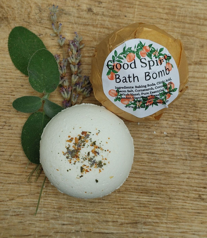 White bath bomb with speckled bits, labeled "Good Spirits" in brown wrap