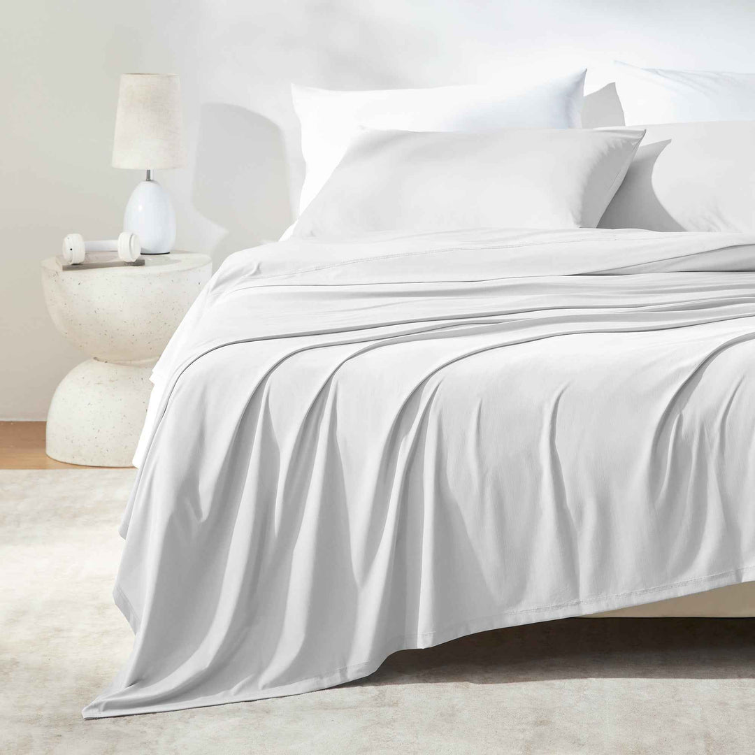 White sheet set on bed with flat sheet and pillowcases in smooth drape