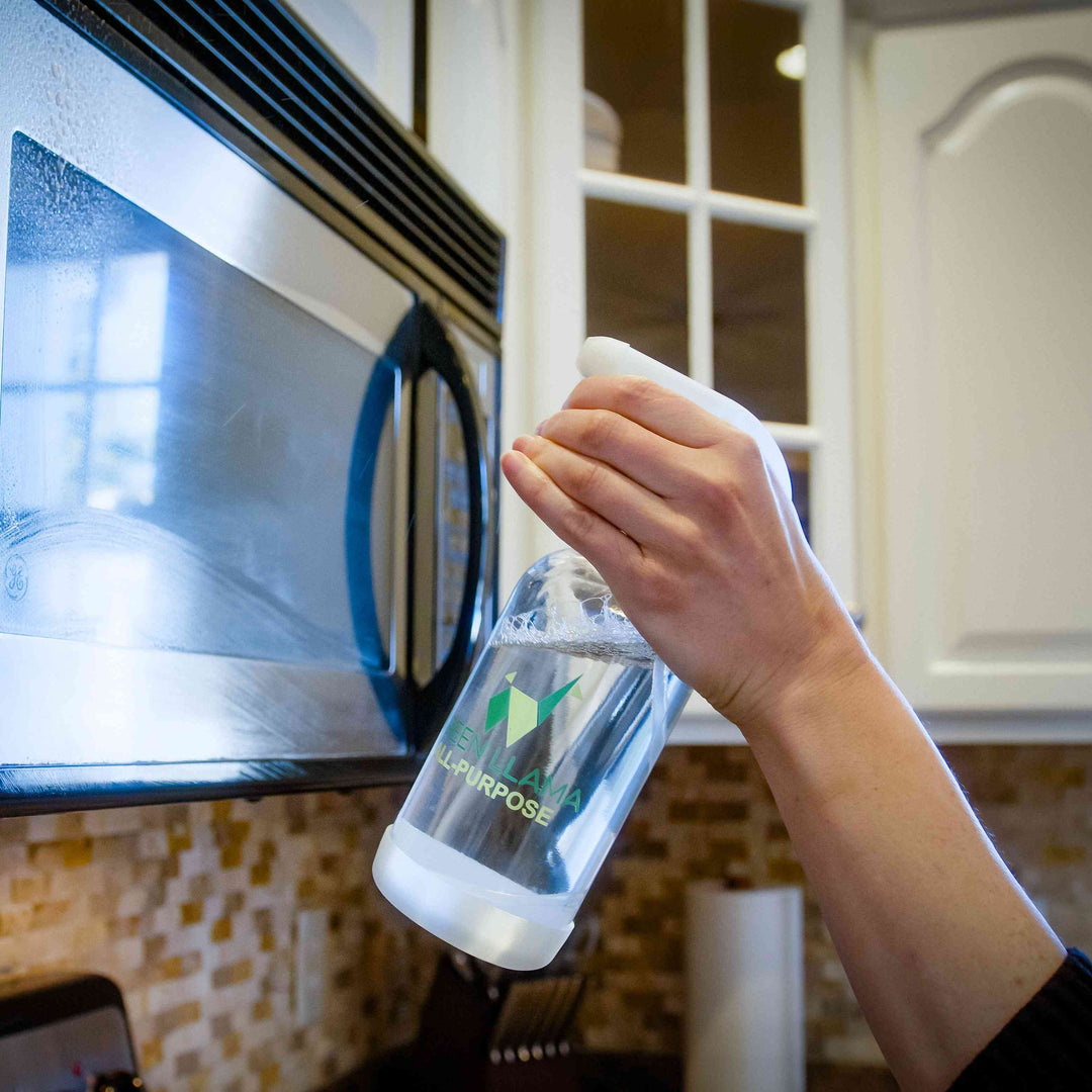 Hand holding a lemongrass cleaner refill bottle near a stovetop