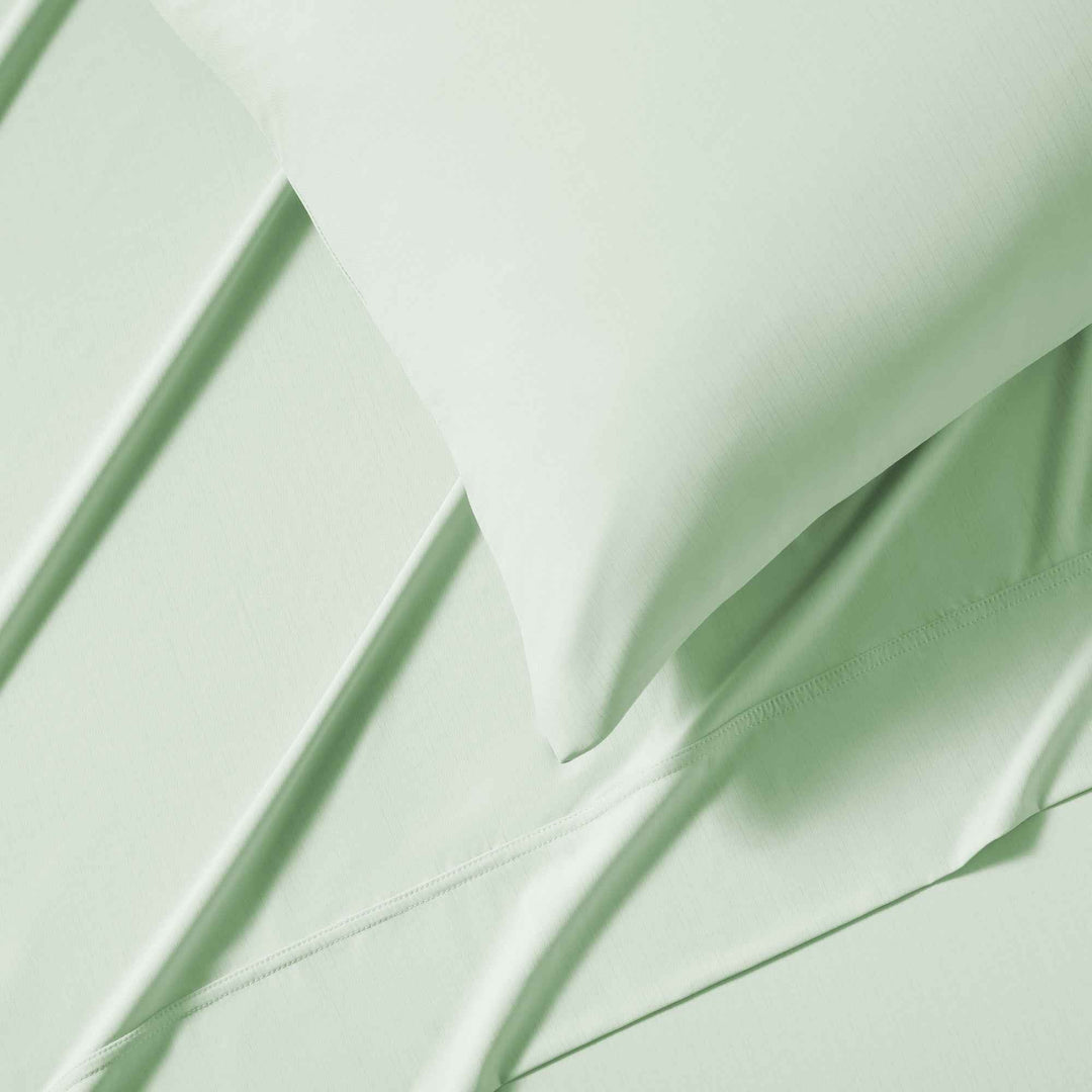 Close-up of light green flat sheet corner with neat stitched seams