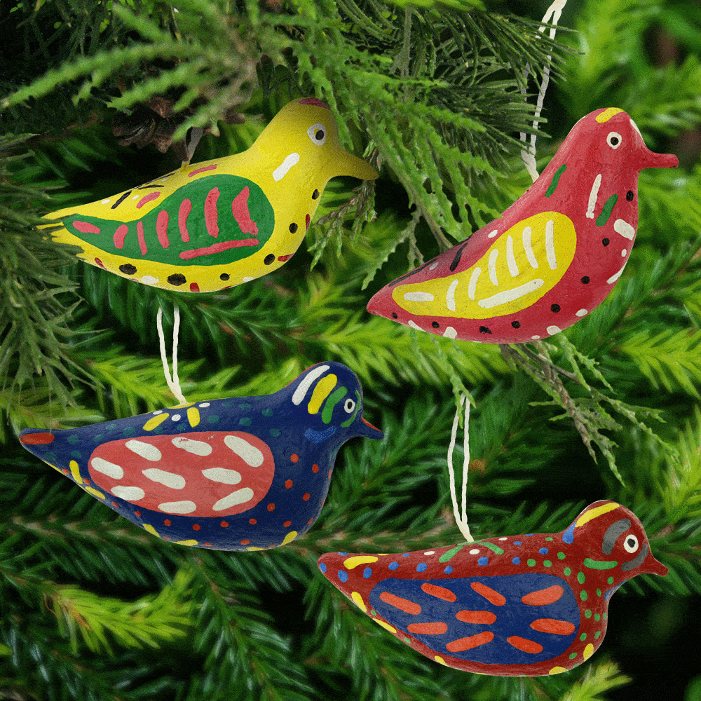 Papier-mache bird ornaments in pink, yellow, and blue on pine branch