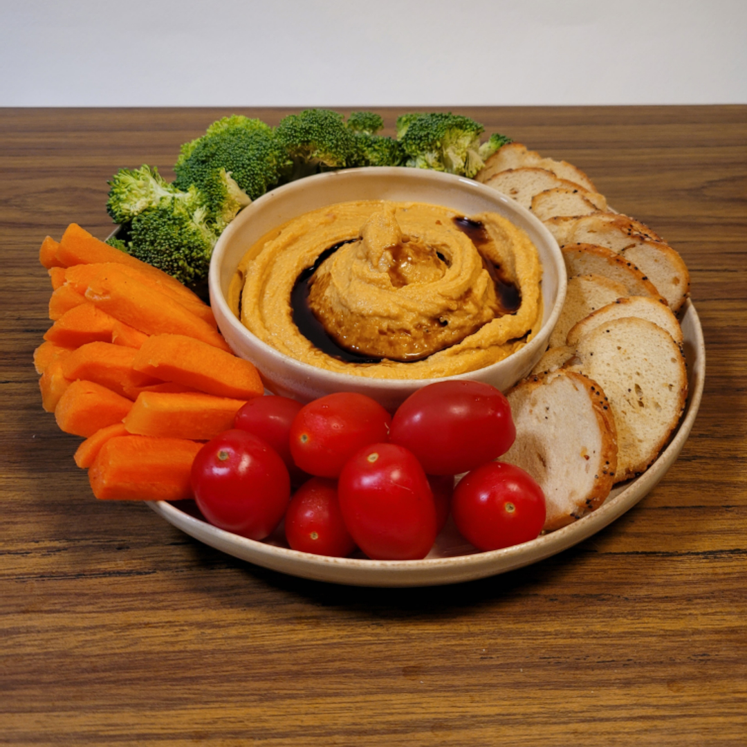 Ceramic dip platter holding hummus-style dip with carrots, tomatoes, and bread slices