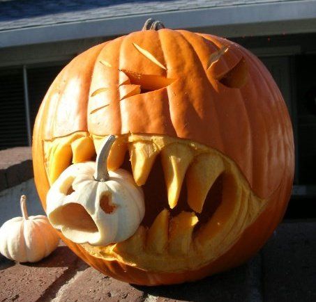 Carved orange jack-o-lantern pumpkin with a face and small white gourds