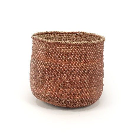 Small round woven basket in rust-brown with braided rim and open top