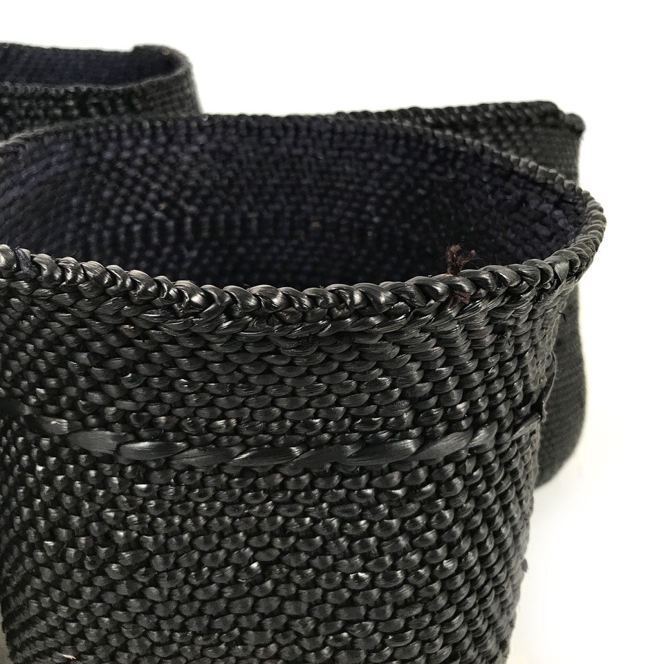 Close-up of dark woven basket with braided rim and tight textured weave