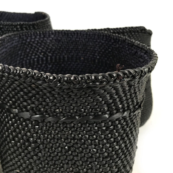 Close-up of dark woven basket with braided rim and tight textured weave
