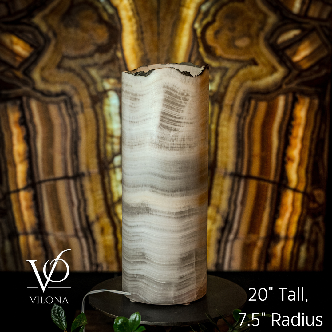 Cylindrical white onyx lamp shade with irregular top on black circular base, front view
