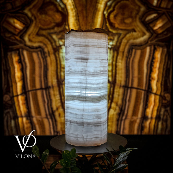 Table lamp with cylindrical onyx shade and round base, white-blue veining beside green leaves