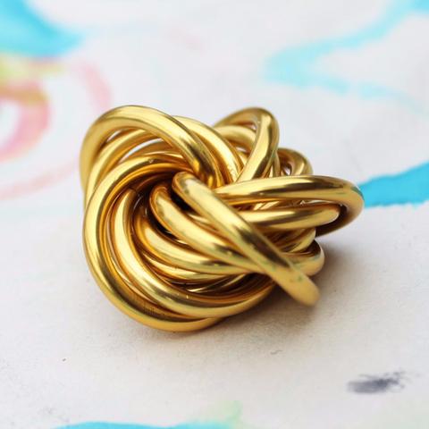 Metallic gold stress fidget ball shaped like a twisted knot.