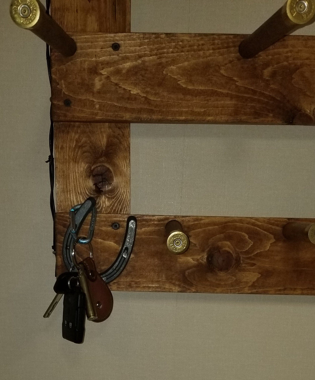 Wooden wall mount with horseshoe-shaped hooks for hanging accessories on a hat organizer