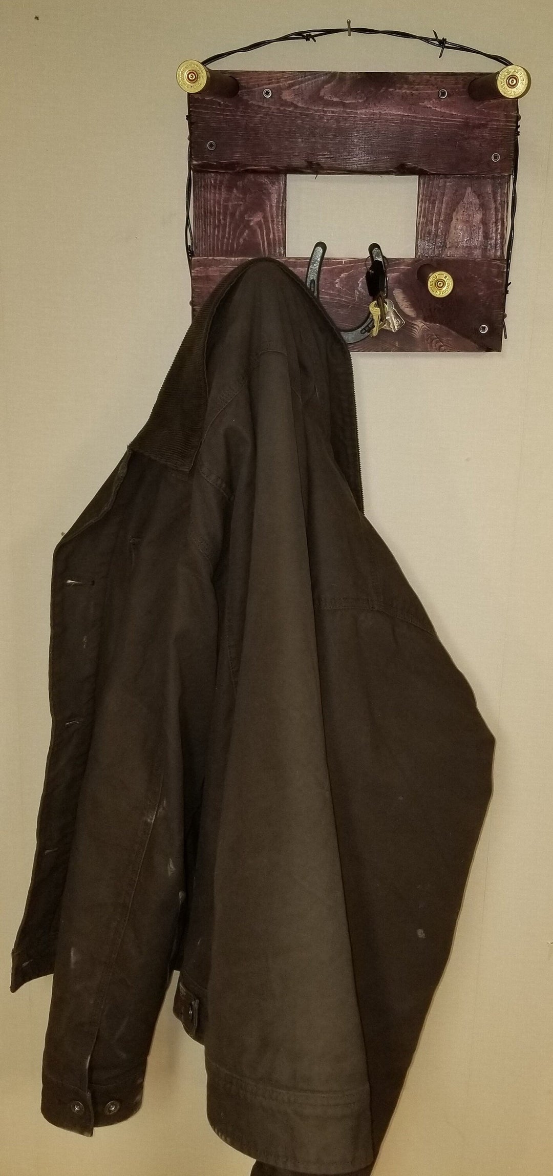 Horizontal wall-hanging western organizer with tan top pocket and black coat on dark panel