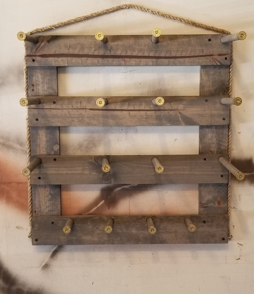 Gray wooden vertical wall organizer with three open shelf panels, metal pegs, and hanging twine