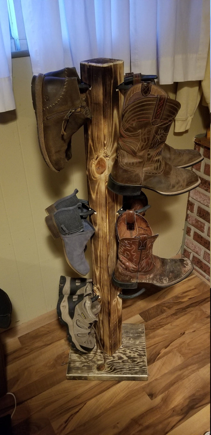 Wooden cowboy boot floor stand displaying multiple boots on side pegs.