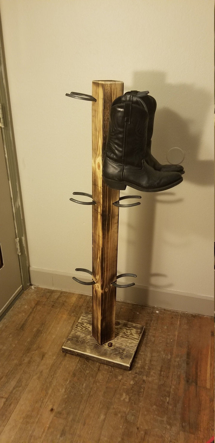 Wooden cowboy boot floor stand with vertical post and 6 side pegs, holding one boot.