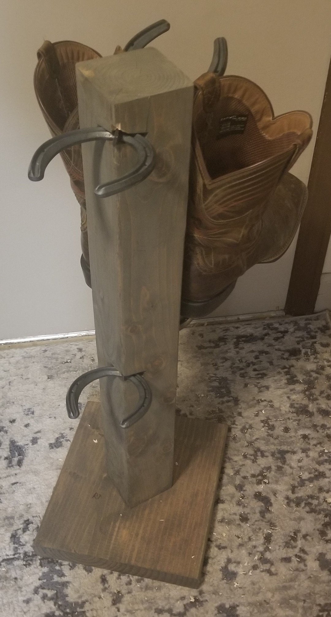 Rustic cowboy boot floor stand with four metal loops and visible boots, wooden base