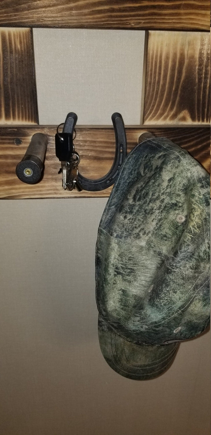 Close-up of wooden wall organizer with central panel, hooks, and dark green hat