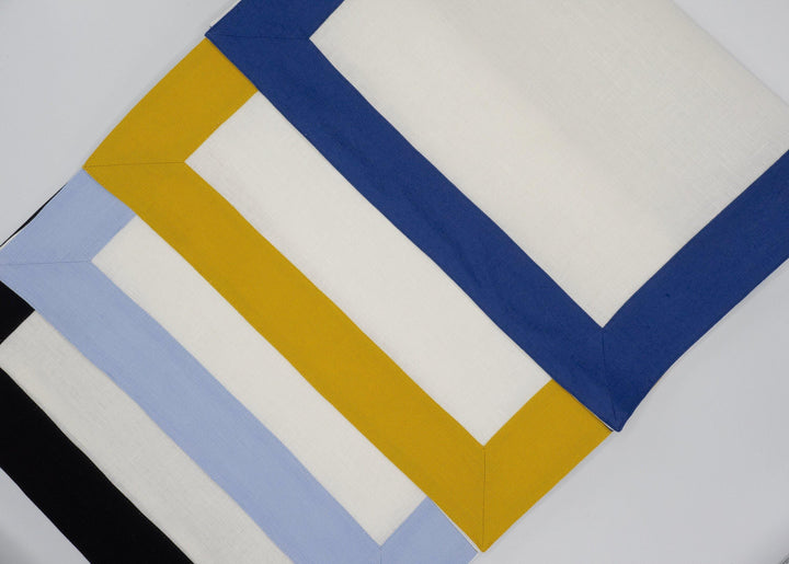 Linen placemats with mustard and navy borders over white panels, folded