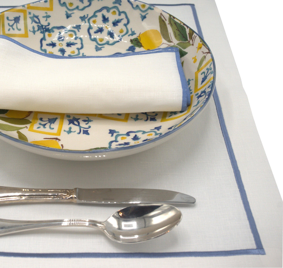 Linen placemat with blue border under folded napkin and cutlery