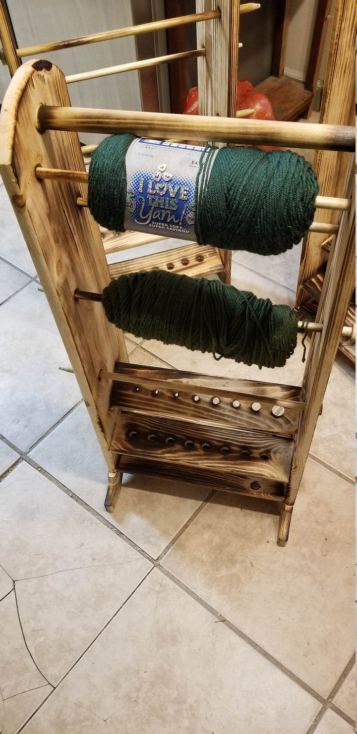 Wooden yarn holder organizer with two green yarn skeins on peg shelves