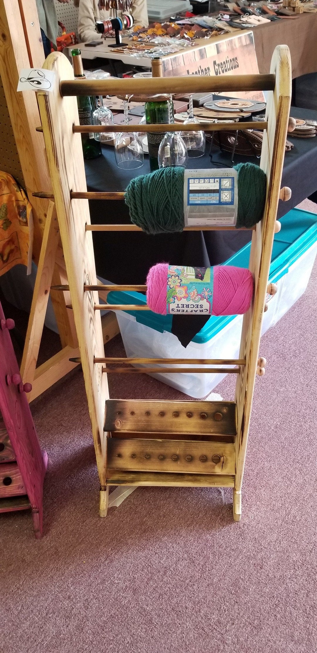 Wooden yarn organizer rack holding skeins on pegs and tiered storage bars