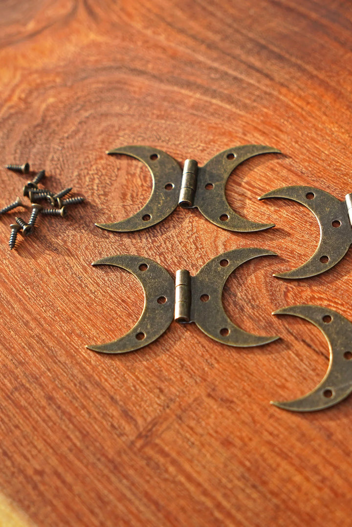 Steel crescent moon hinge parts with screws, bronze finish on wood grain