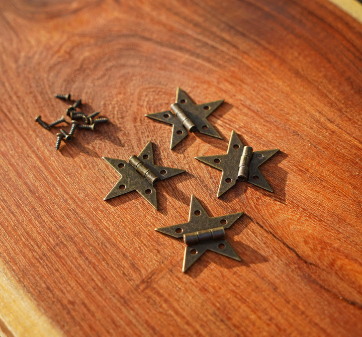 Set of bronze star hinges laid on a wooden tabletop
