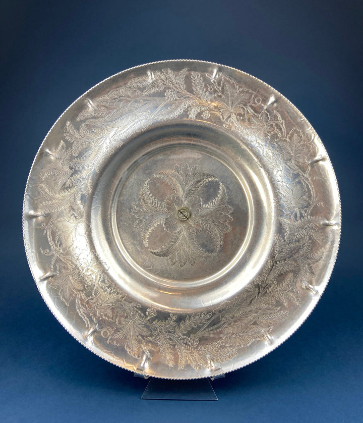 Silver metal serving dish with engraved floral and leaf pattern, round footed center