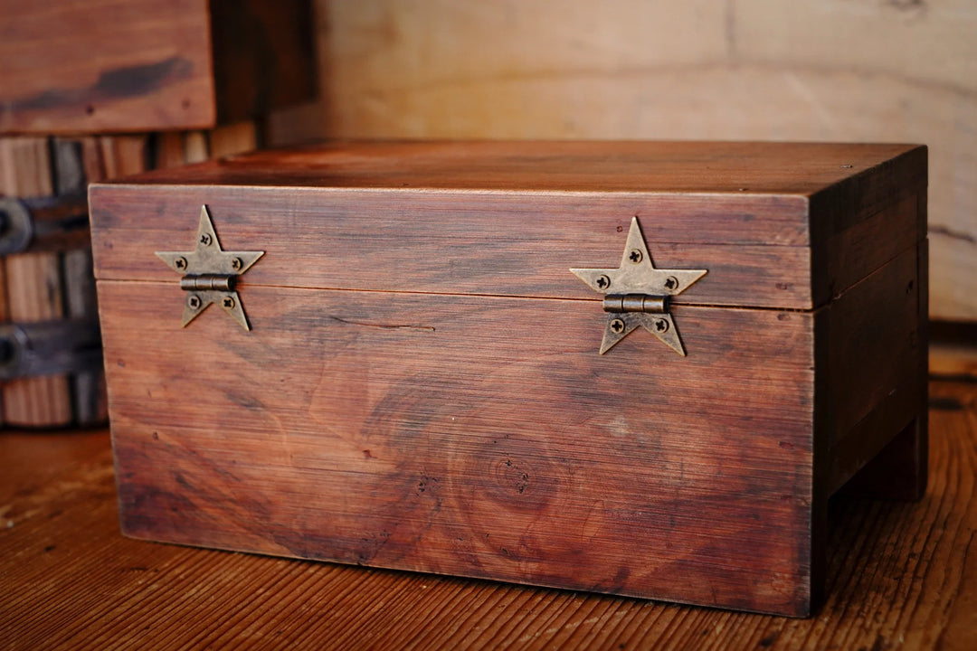 Two bronze star hinges mounted on a wooden box front