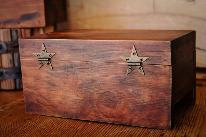 Two bronze star hinges mounted on a wooden box front
