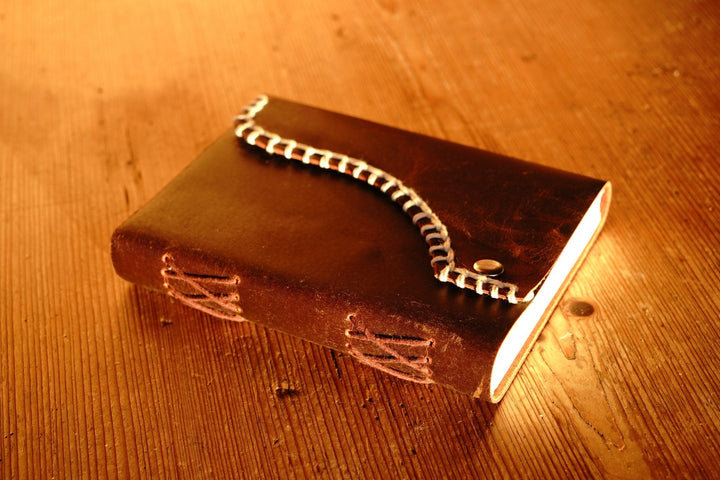 Brown distressed leather journal with white blanket edge stitching and embossed details