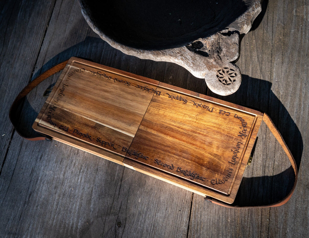 Folding acacia cutting board with utensil slots and open compartments, viewed from above
