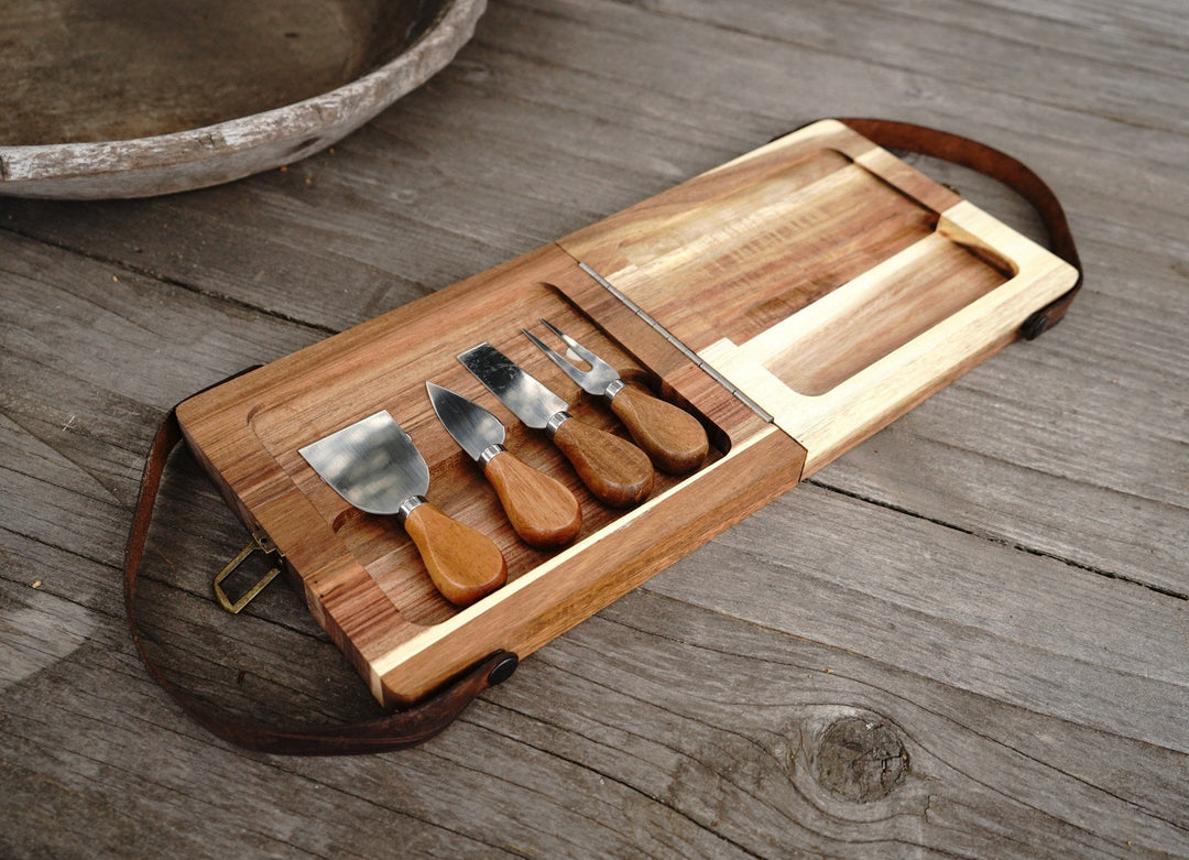 Open acacia folding cutting board with knives and utensils in built-in holders