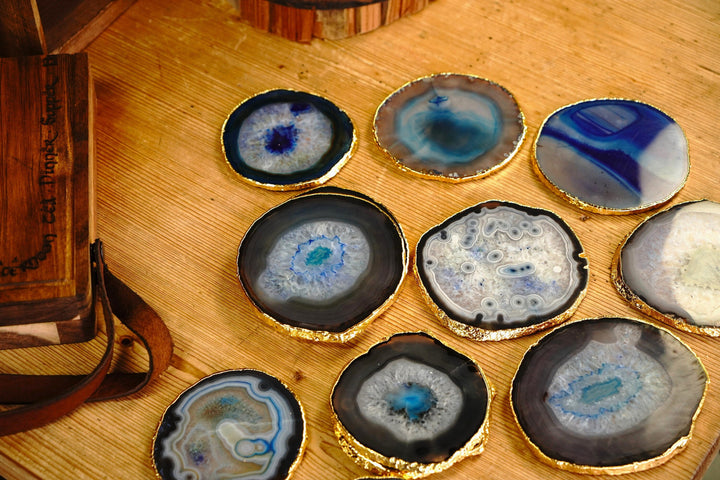 Multiple round blue agate coasters with gold rims, arranged on a wooden board