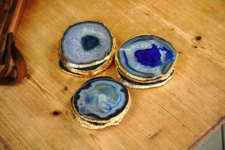 Set of round blue agate coasters with gold edges, placed on a wooden surface