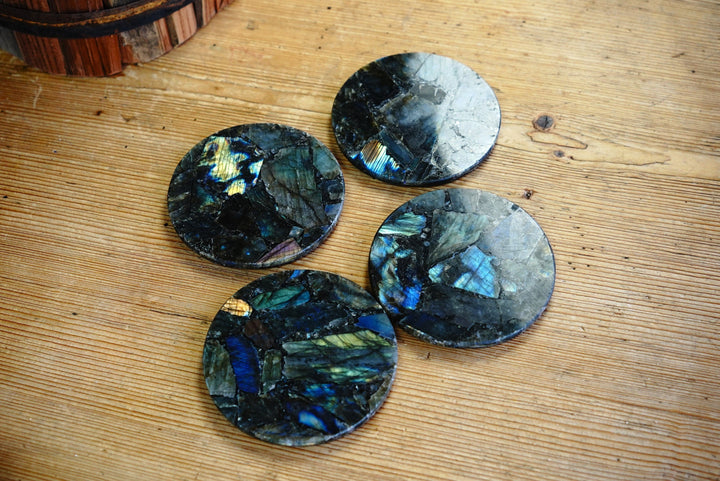 Round labradorite coasters on wooden surface, blue-green iridescent patterns