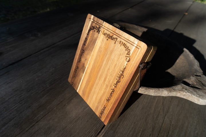 Acacia wood folding cutting board with leather carry handle and engraved front and edges