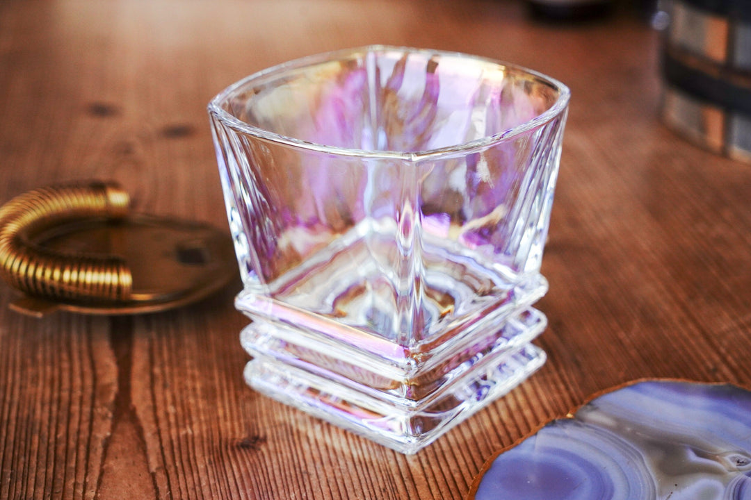 Iridescent lowball whiskey glass with stacked ridges, front view on wooden table