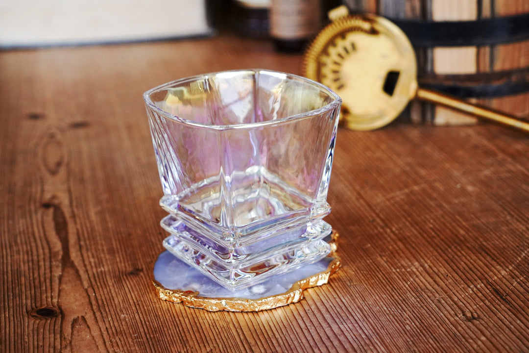 Iridescent lowball whiskey glass with faceted sides and stacked band base, side angle