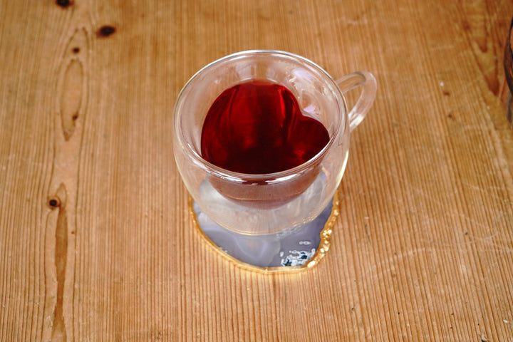 Clear double-walled glass mug filled with red tea, visible handle and rim