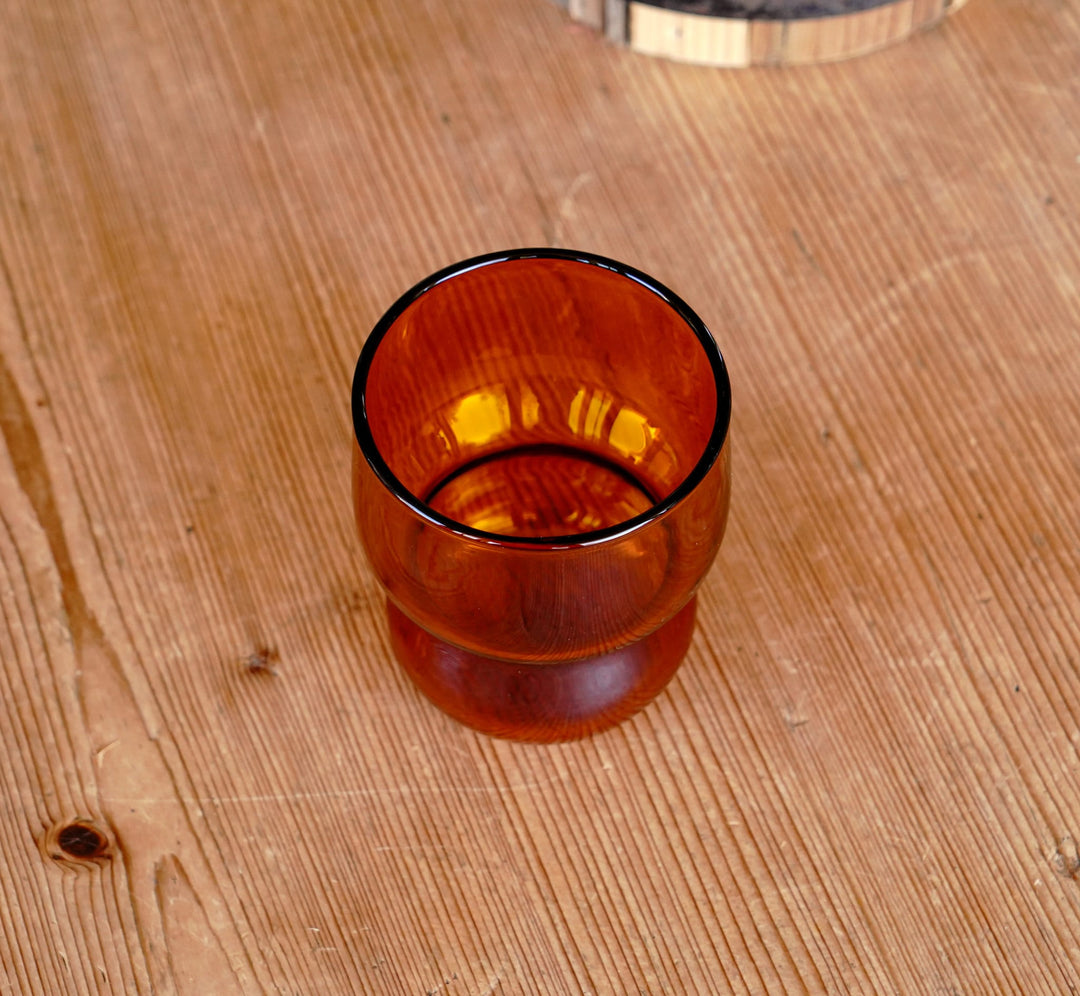 Amber orange bubble juice glass cup on a wooden board