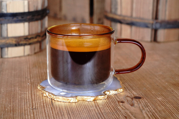 Amber double-walled glass mug with handle, coffee drink inside