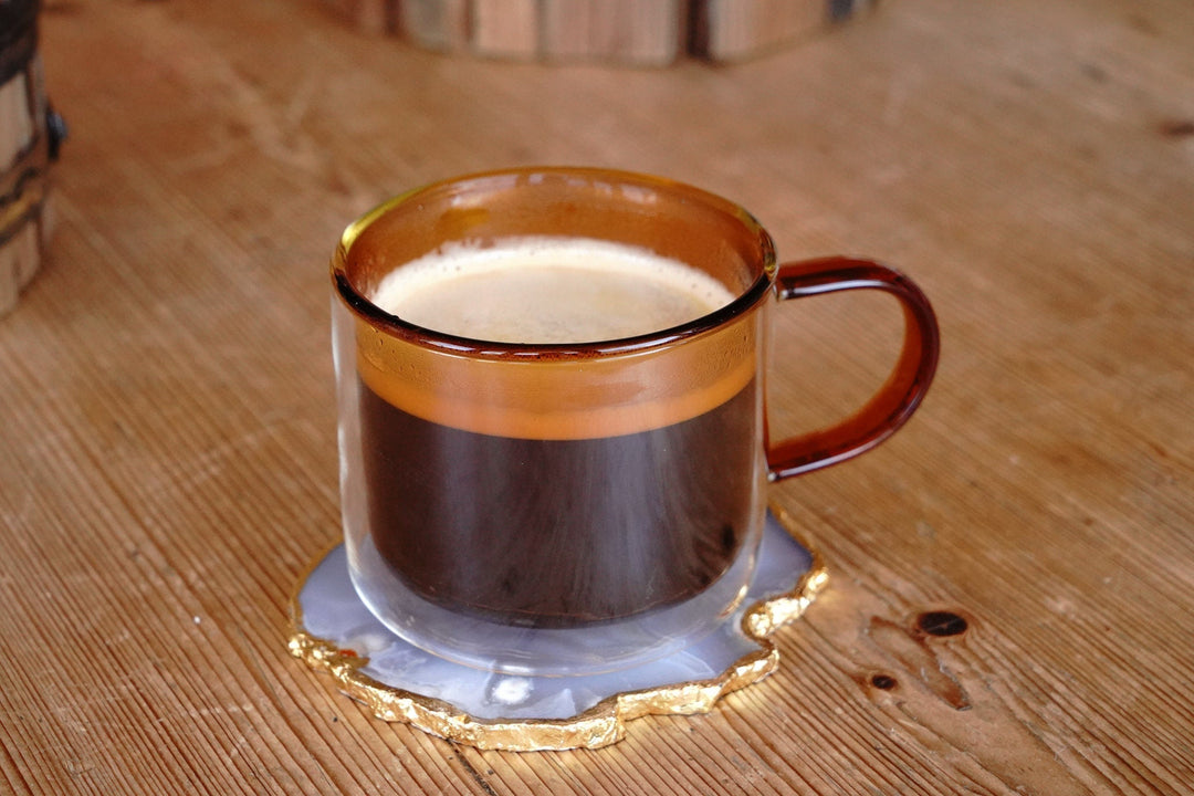 Amber double-walled glass mug with handle, frothy drink visible