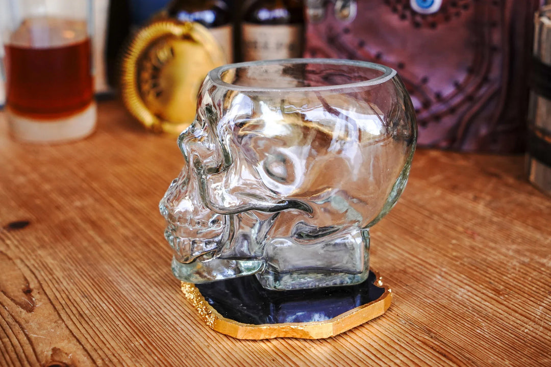 Clear skull whiskey glass with detailed face design on black-and-gold coaster