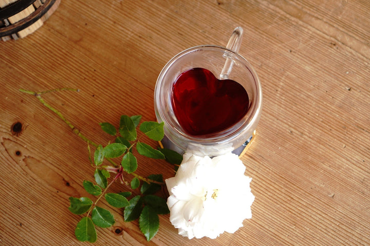 Clear double-walled glass mug with red tea and heart-shaped insert