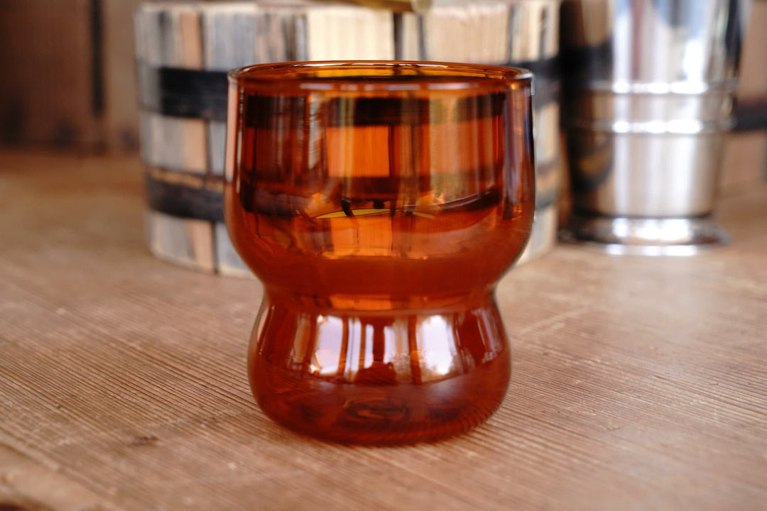 Amber orange bubble juice glass on a wooden tabletop