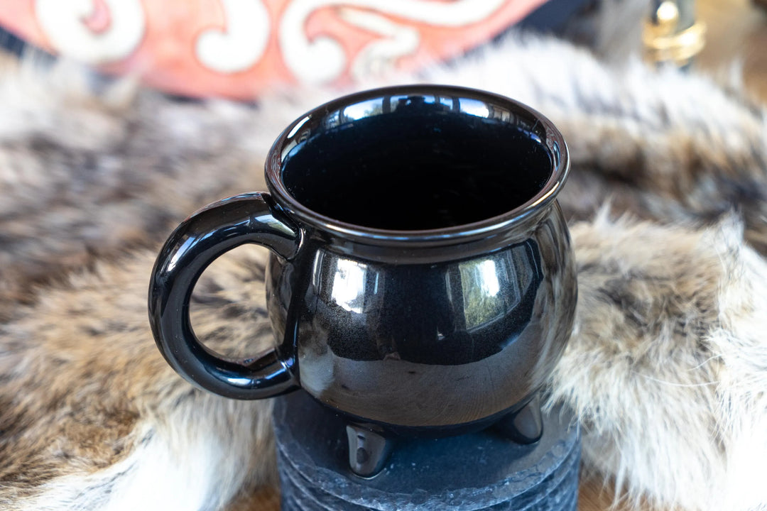 Black ceramic cauldron-style coffee mug with side handle, close-up on top opening.